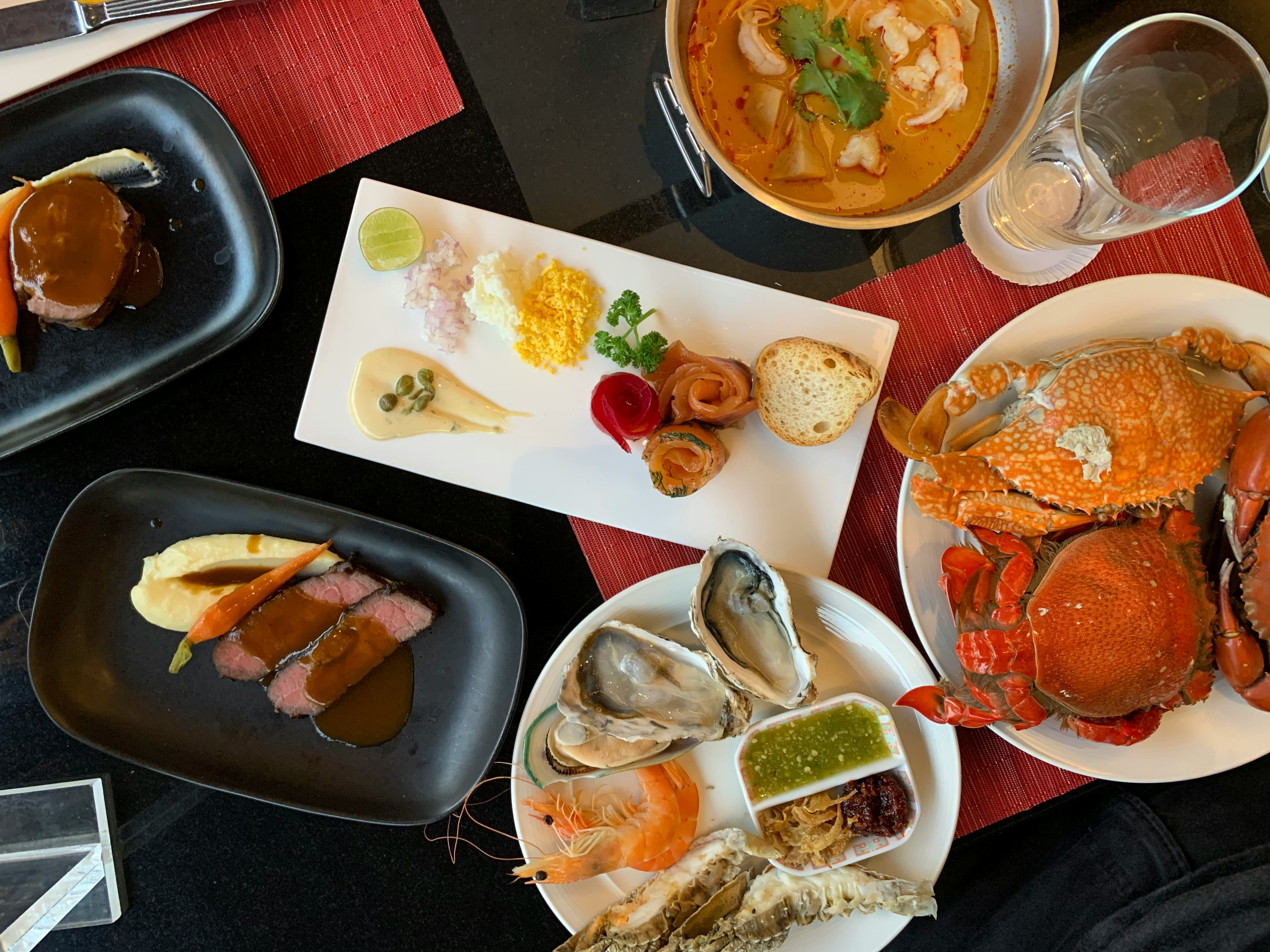 Plates of fresh seafood including oysters, crab, shrimp, and crab cakes served with sauces at a coastal restaurant.