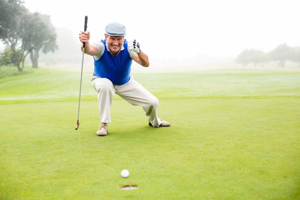 Happy golfer cheering on putting green on a foggy day at the golf course